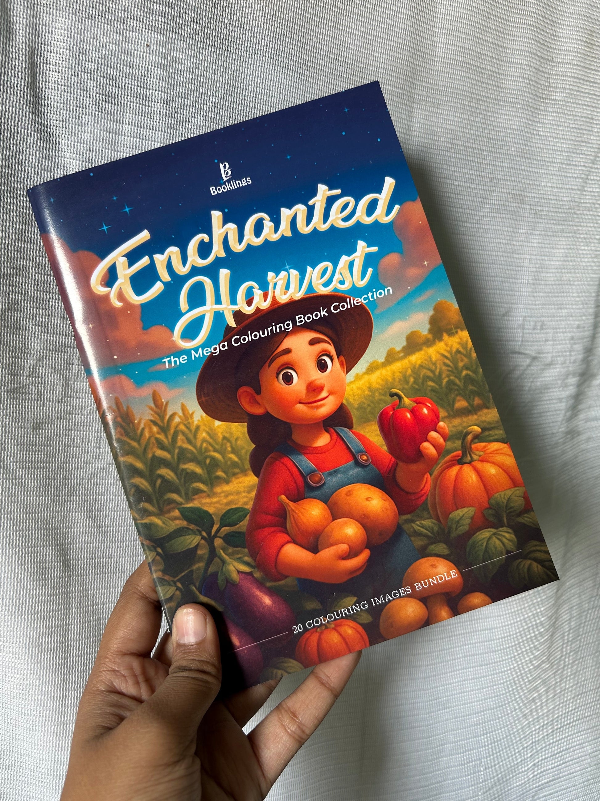 Book titled 'Enchanted Harvest' held by a hand on a light gray fabric background