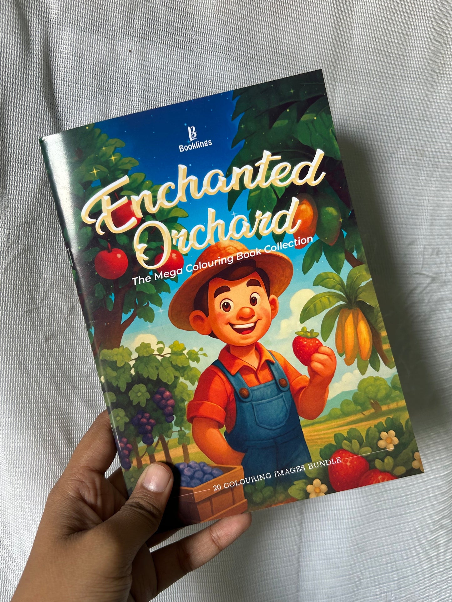 Hand holding a board game box titled 'Enchanted Orchard' on a light gray surface.